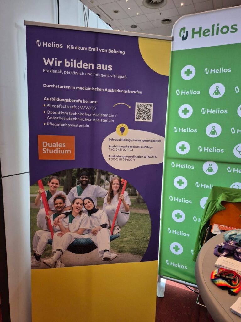 Ein Werbebanner der Helios Klinik zeigt Informationen über duale Studiengänge in verschiedenen medizinischen Bereichen. Der automatisch gespeicherte Entwurf zeigt lächelnde junge Menschen in medizinischen Uniformen, die auf einer Wiese sitzen und Mappen halten.